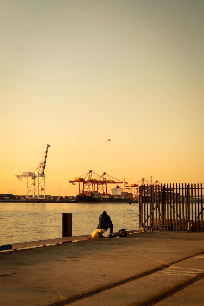 A peaceful evening scene at Fremantle Port with a silhouette of a fisherman against a vibrant sunset.
